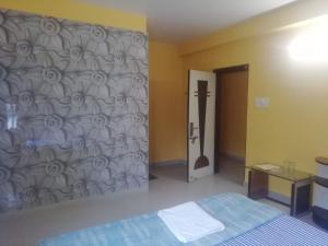 a bedroom with a bed and a wall at Zeromiles Hotel Prasant in Digha
