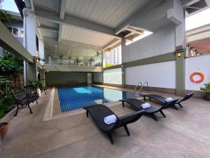 a swimming pool in a building with chairs around it at Boss Mansion in Bangkok