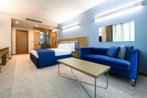 una camera d'albergo con un letto e un divano blu di La Quinta by Wyndham Istanbul Gunesli a Istanbul