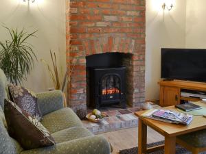 a living room with a fireplace with a couch and a television at The Forge in Tumby