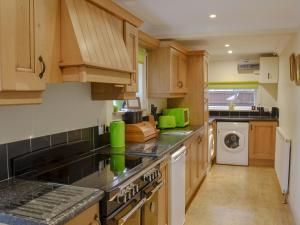 a kitchen with wooden cabinets and a washer and dryer at The Forge in Tumby