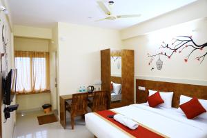 a hotel room with two beds and a desk at Sasthi Suites in Bangalore