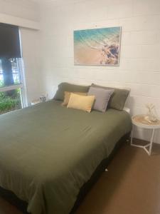 Un dormitorio con una gran cama verde y una mesa en Villa Manyana - Coastal Getaway - Blueys Beach, en Blueys Beach