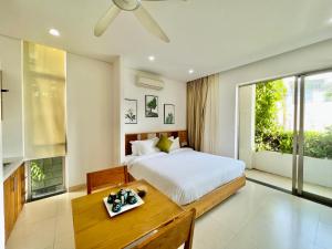 a bedroom with a bed and a table and a window at Babylon Garden Da Nang in Danang