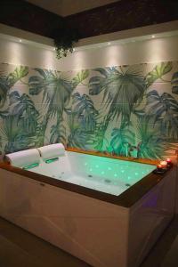 a bath tub with a mural of palm trees on a wall at Terra Mia Suite in Catania
