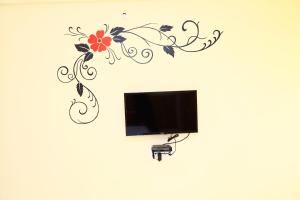 a tv on a wall with a flower design on it at Sasthi Suites in Bangalore