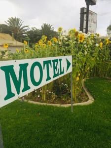 a sign in front of a garden with flowers at Bakery Park Motor Inn in Tocumwal