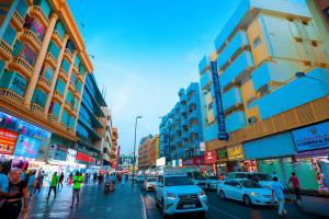 AL KARNAK HOTEL - BRANCH في دبي: شارع المدينة مزدحم بالسيارات والناس والمباني