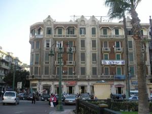a large building with cars parked in front of it at Transit Alexandria Hostel in Alexandria