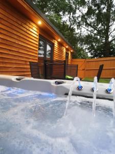 una bañera de hidromasaje en un patio trasero con fuente de agua en Lake District and Eden Valley Thornhill Lodge en Long Marton