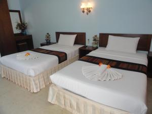 two beds in a hotel room with white sheets at Vacation House in Klong Muang Beach