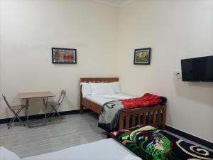 a bedroom with a bed and a table and a television at Chibuba Airport Accommodation in Dar es Salaam