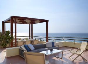 a balcony with a couch and chairs and the ocean at Rhodes Bay Hotel & Spa in Ixia