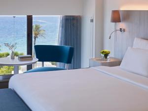 a hotel room with a white bed and a blue chair at Rhodes Bay Hotel & Spa in Ixia