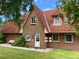 a brick house with a red roof and a bench at Ferienwohnung "Neptun" im Haus Tjark in Sankt Peter-Ording