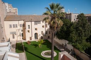 un palmier devant un bâtiment avec une cour dans l'établissement Hotel Vittorio Veneto, à Raguse