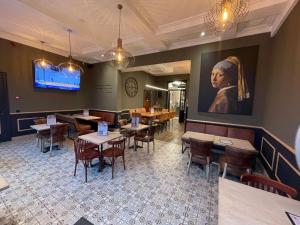 a restaurant with tables and chairs and a painting on the wall at Hôtel Maison Demelenne in Hotton