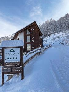 un panneau dans la neige devant un lodge dans l'établissement Savoia Resort, à Bardonnèche