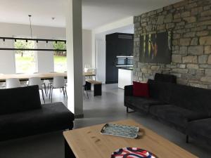a living room with black furniture and a stone wall at Gîte 'Il y a' 11 à 13 pers #Nature #Familles #Calme #Pas d'abus d'alcool in Marche-en-Famenne