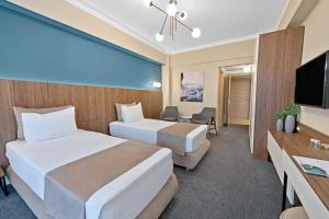 a hotel room with two beds and a flat screen tv at Hotel Oxford in Mamaia