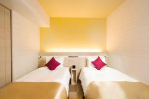 two beds in a small room with red pillows at Best Western Hotel Fino Tokyo Akasaka in Tokyo