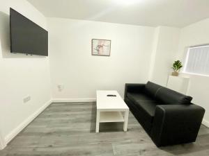 a living room with a black couch and a white table at Tong Apartments in Leeds