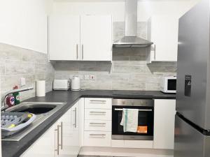 a white kitchen with a sink and a stove at Tong Apartments in Leeds