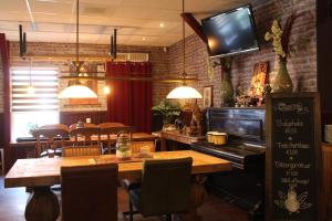 a restaurant with a table and a television on the wall at Hotel,cafe,biljart POT in Groenlo