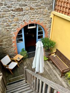 a patio with a umbrella and a table and a bench at HOTEL KAN AVEL in Saint-Lunaire