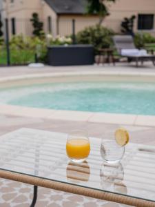 two glasses of orange juice sitting on a table next to a pool at La Maison de Jacqueline in Vosne-Romanée