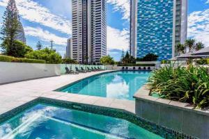 a swimming pool with chairs and a building at Sea Views Broadbeach in Gold Coast