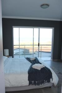 a bedroom with a white bed with a large window at Atlantic Dunes Unit 11, Self Catering in Rand Rifles