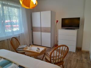 ein Wohnzimmer mit einem TV, einem Tisch und Stühlen in der Unterkunft Ferienwohnung Sonne in Waidhofen an der Ybbs