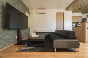 a living room with a couch and a tv at マークヴィラ諏訪湖 siteA in Shimo-suwa