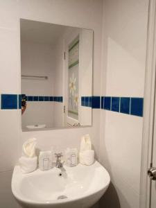 a white bathroom with a sink and a mirror at Nangnon Hill Hug Hotel in Ban Pa Muat