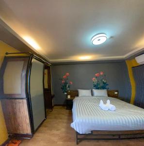 Nangnon Hill Hug Hotel في Ban Pa Muat: غرفة نوم بسرير مع شراشف بيضاء وزهور
