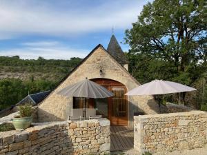 een stenen gebouw met twee parasols ervoor bij Domaine de Galoubet, Lot , Gîtes de charme in Beaumat