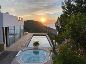 a house with a swimming pool and a sunset at Design Studio Cap Rubio Ibiza in Na Xamena