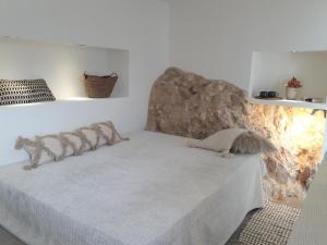 a bedroom with a white bed with a stone wall at Design Studio Cap Rubio Ibiza in Na Xamena