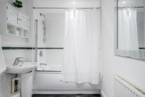 a white bathroom with a shower and a sink at Bright and cozy 2-Bed Apartment in Dagenham in Dagenham