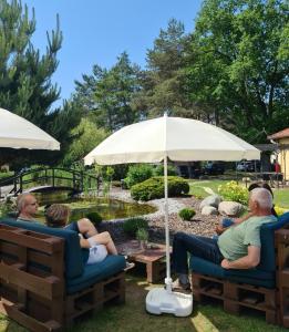 a group of people sitting on chairs under an umbrella at Hotel Pommerscher Hof in Zinnowitz