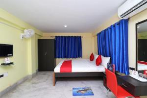 um quarto com uma cama com cortinas azuis e uma cadeira vermelha em OYO Maa Tara Guest House Near Acropolis Mall em Jādabpur