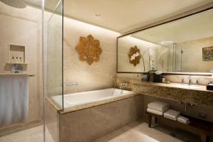 a bathroom with a tub and a sink and a mirror at InterContinental Bali Resort, an IHG Hotel in Jimbaran