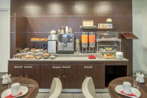 a kitchen with two tables and a counter with food at Citadines République Paris in Paris