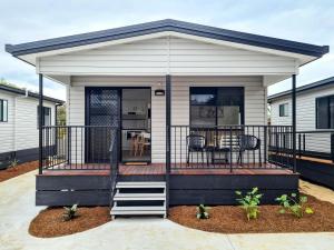 a tiny house with a deck with a table at Club Byron Accommodation in Byron Bay