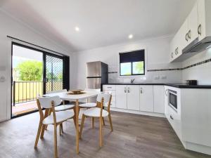 a kitchen with white cabinets and a table and chairs at Club Byron Accommodation in Byron Bay