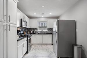 a kitchen with white cabinets and a stainless steel refrigerator at Pool Escape Nr Med Center, Galleria, Nrg Games in Houston