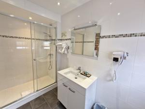 Un baño blanco con ducha y lavabo. en Hôtel Océanic - Grands Magasins, en París 67 fotos más