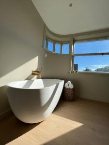 baño con una gran bañera blanca y ventana en Tuss, en Cortrique