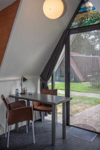 einen Tisch und Stühle in einem Zimmer mit Fenster in der Unterkunft Hotelhuisjes Aartswoud in Aartswoud